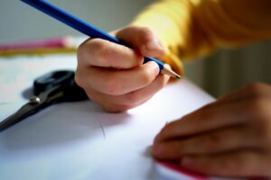 鉛筆を持って机に向かう小学生の手元。英検の勉強をするイメージ