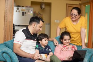 ノートパソコンを家族で一緒にのぞきながらオンライン英会話レッスンを受ける子ども