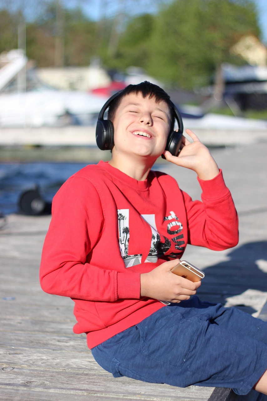 ヘッドホンで音楽を聴いて笑顔の男の子。英語のリスニング学習のイメージ